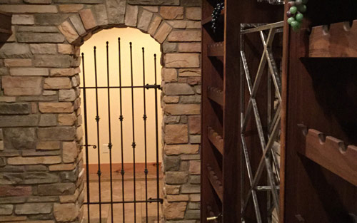 Stone arch doorway with iron gate for custom built wine cellar by Mountain View Corporation in Glendale Colorado